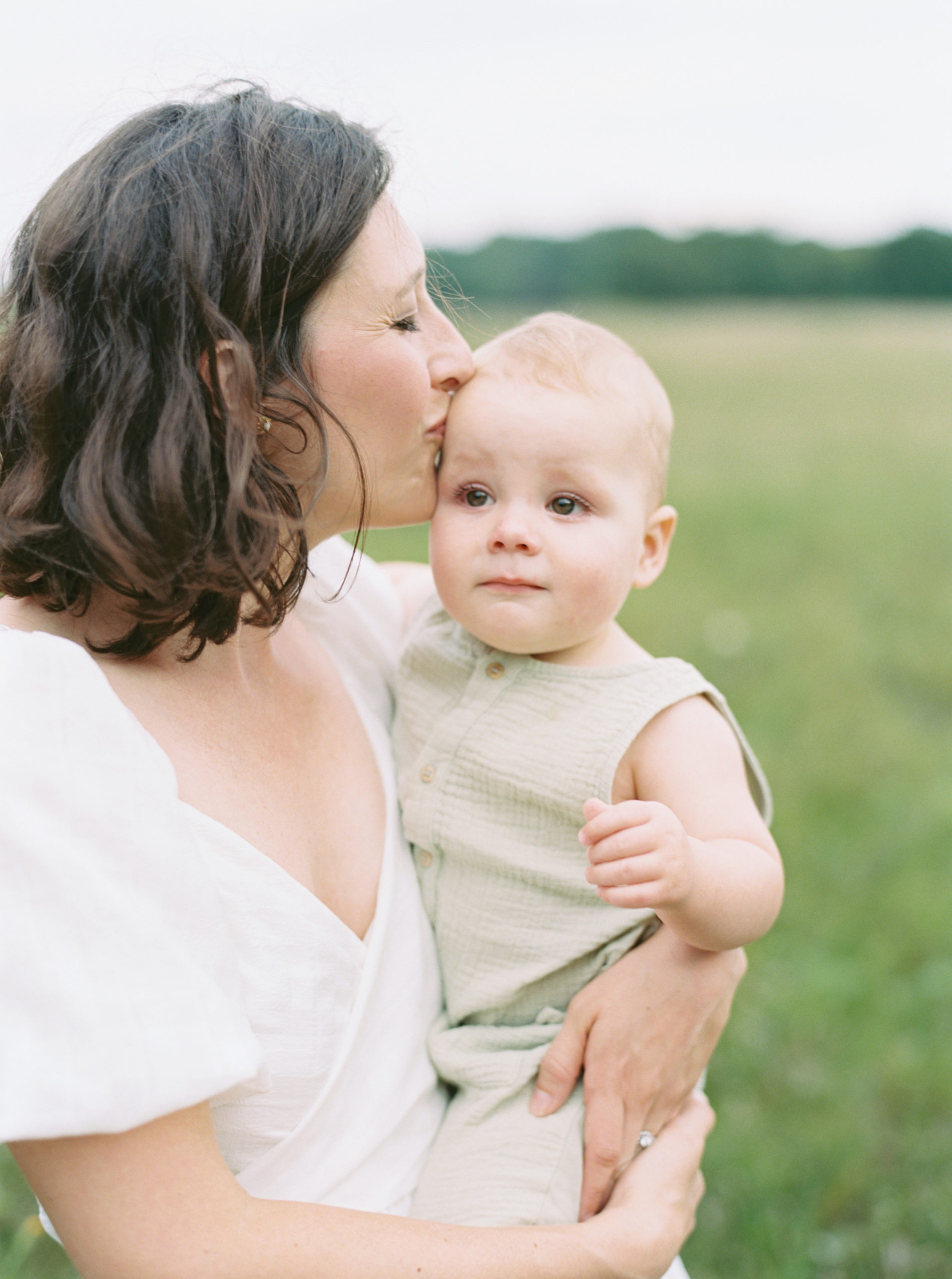 mother holding her baby in a grassy field for family portraits