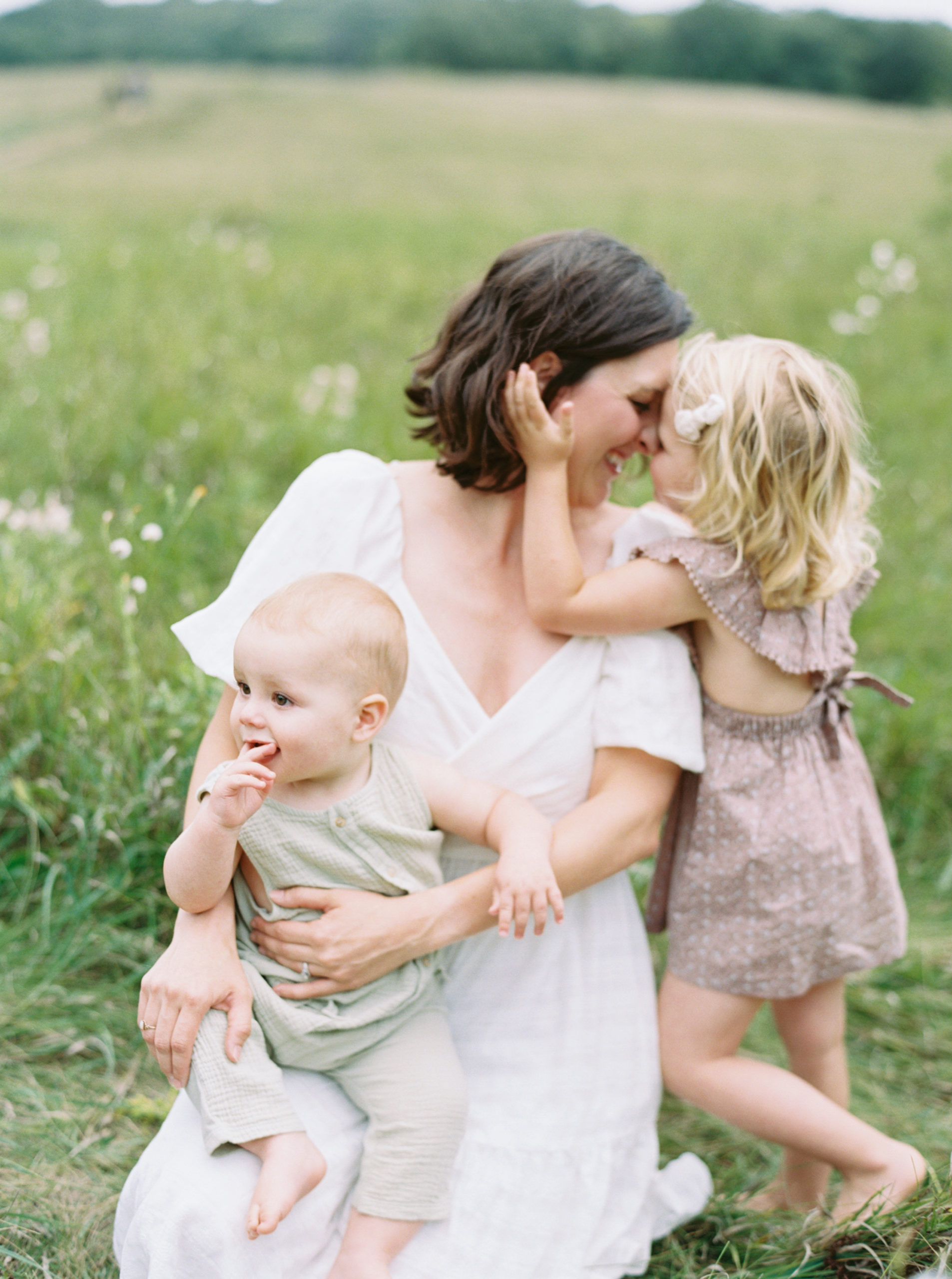 mother holding her baby in a grassy field for family portraits