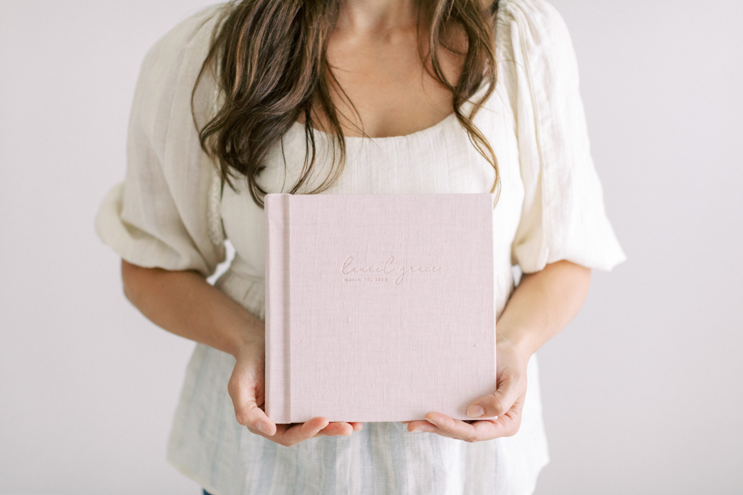 Milwaukee newborn photographer holding newborn baby album with a blush linen cover