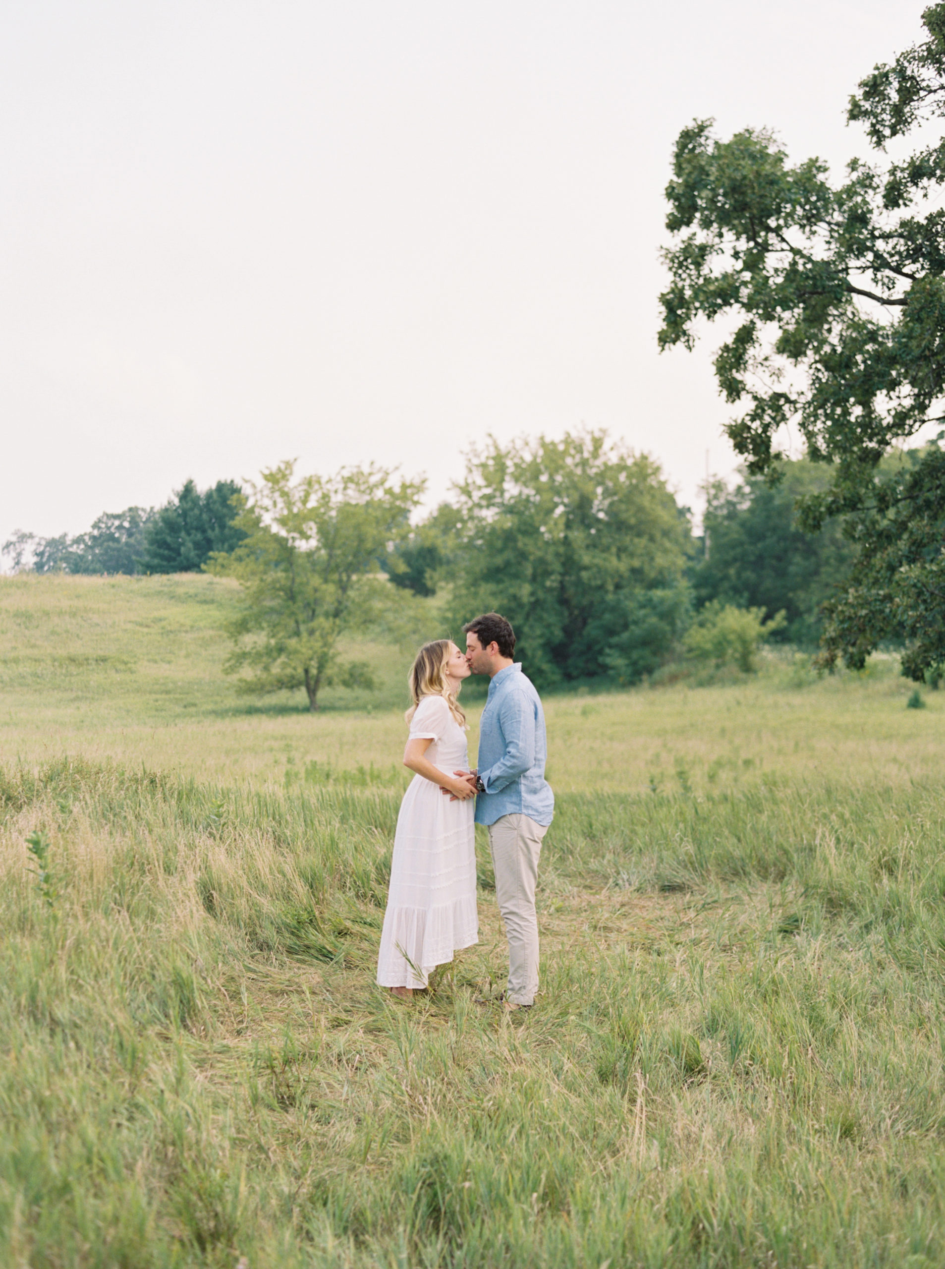 photo of pregnant mother snuggling husband in field taken by Milwaukee Maternity Photographer, Talia Laird Photography