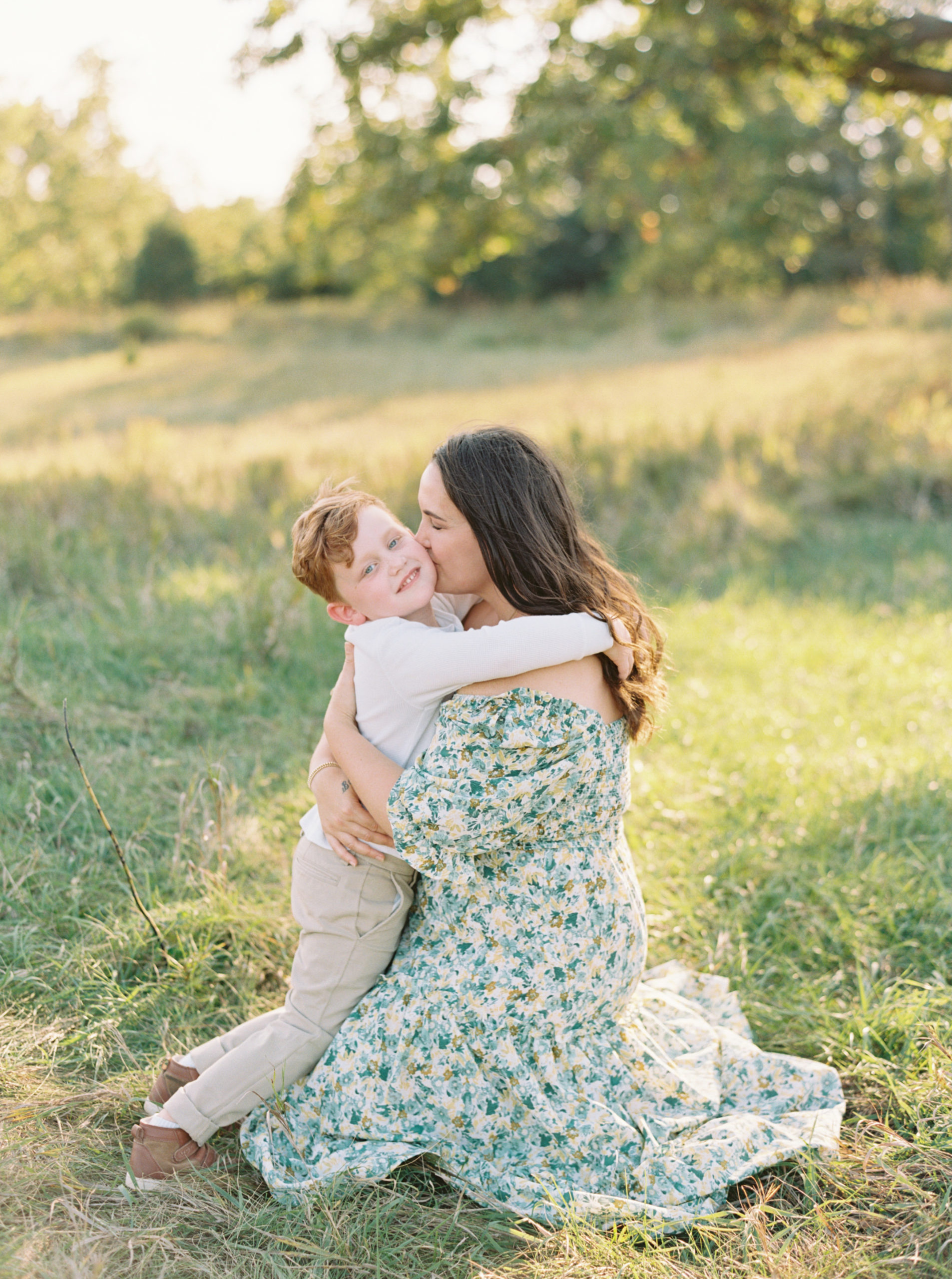 Mother and Son cuddling in a grassy green field setting in Shorewood in the summer