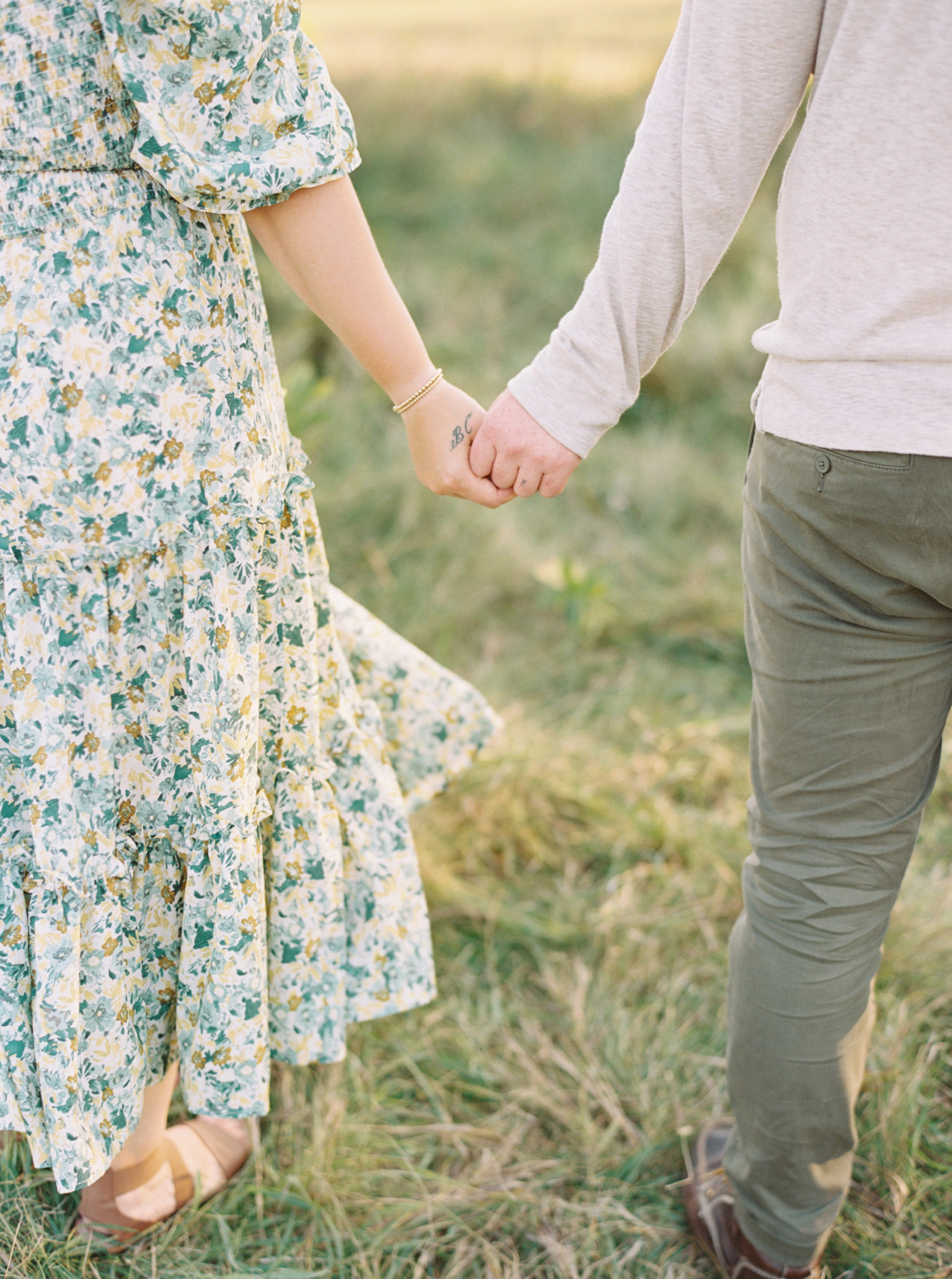 Holding hands in a grassy green field setting in Shorewood in the summer