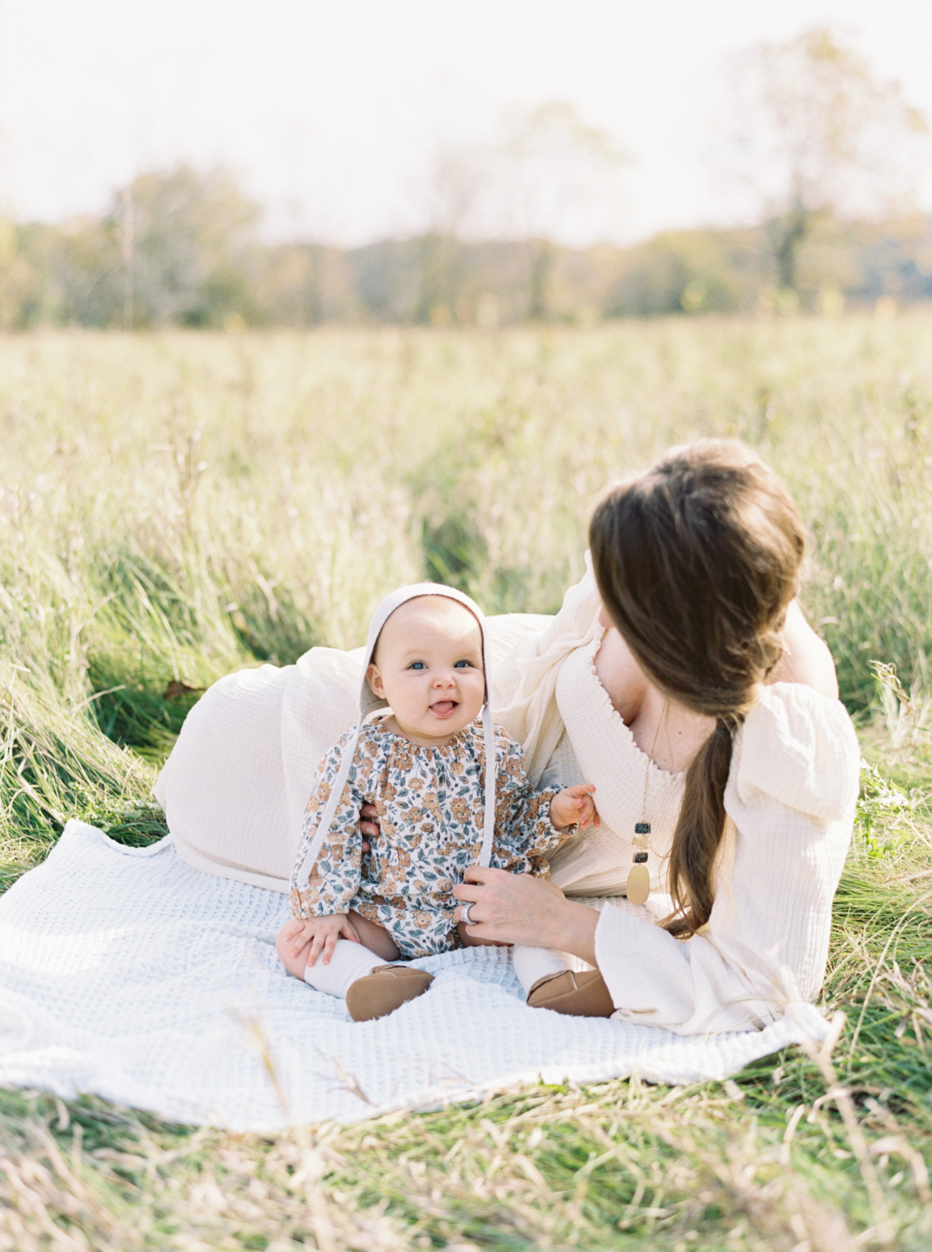 A Mother cuddles her baby in a grassy Hartland field on a beautiful Fall afternoon