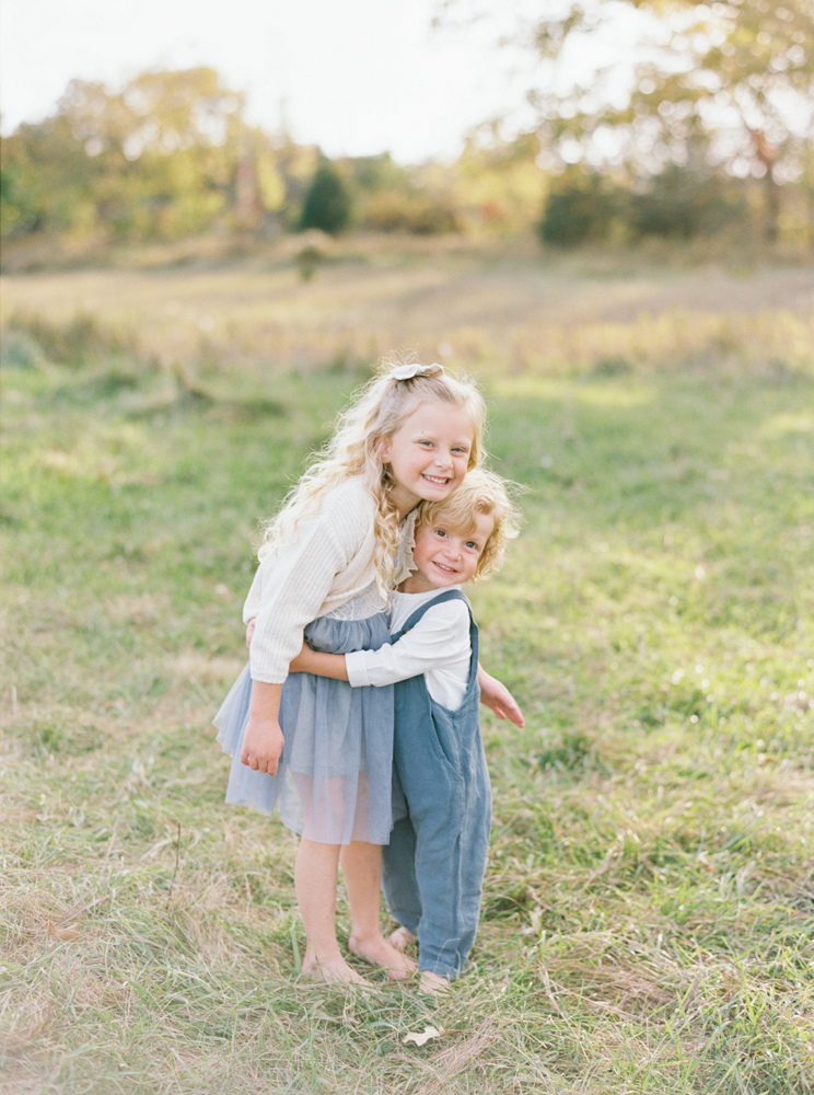 Brother and sister cuddle in beautiful, green, grassy Milwaukee field