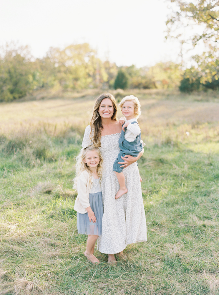 Mother cuddles her son and daughter in beautiful, green, grassy Milwaukee field