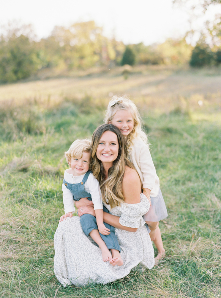 Mother cuddles her son and daughter in beautiful, green, grassy Milwaukee field