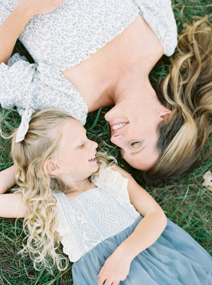 Mother cuddles daughter in beautiful, green, grassy Milwaukee field