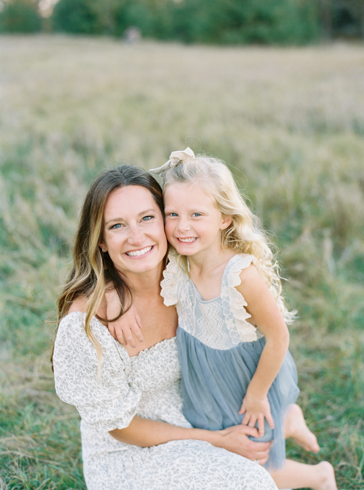 Mother cuddles daughter in beautiful, green, grassy Milwaukee field