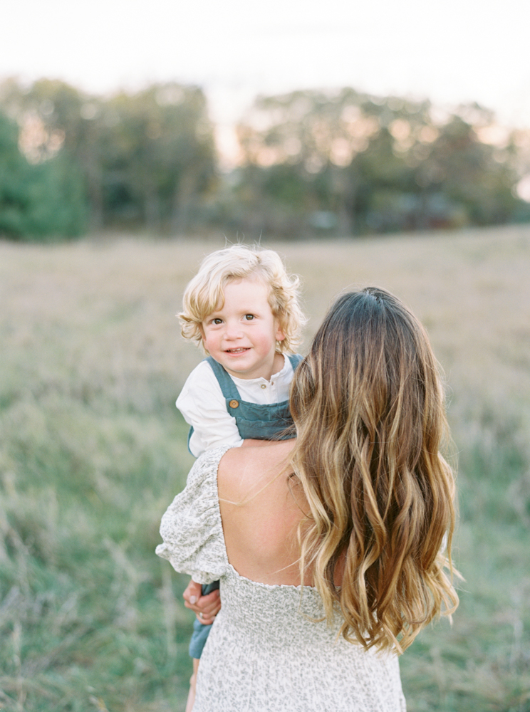 Mother cuddles son in beautiful, green, grassy Milwaukee field