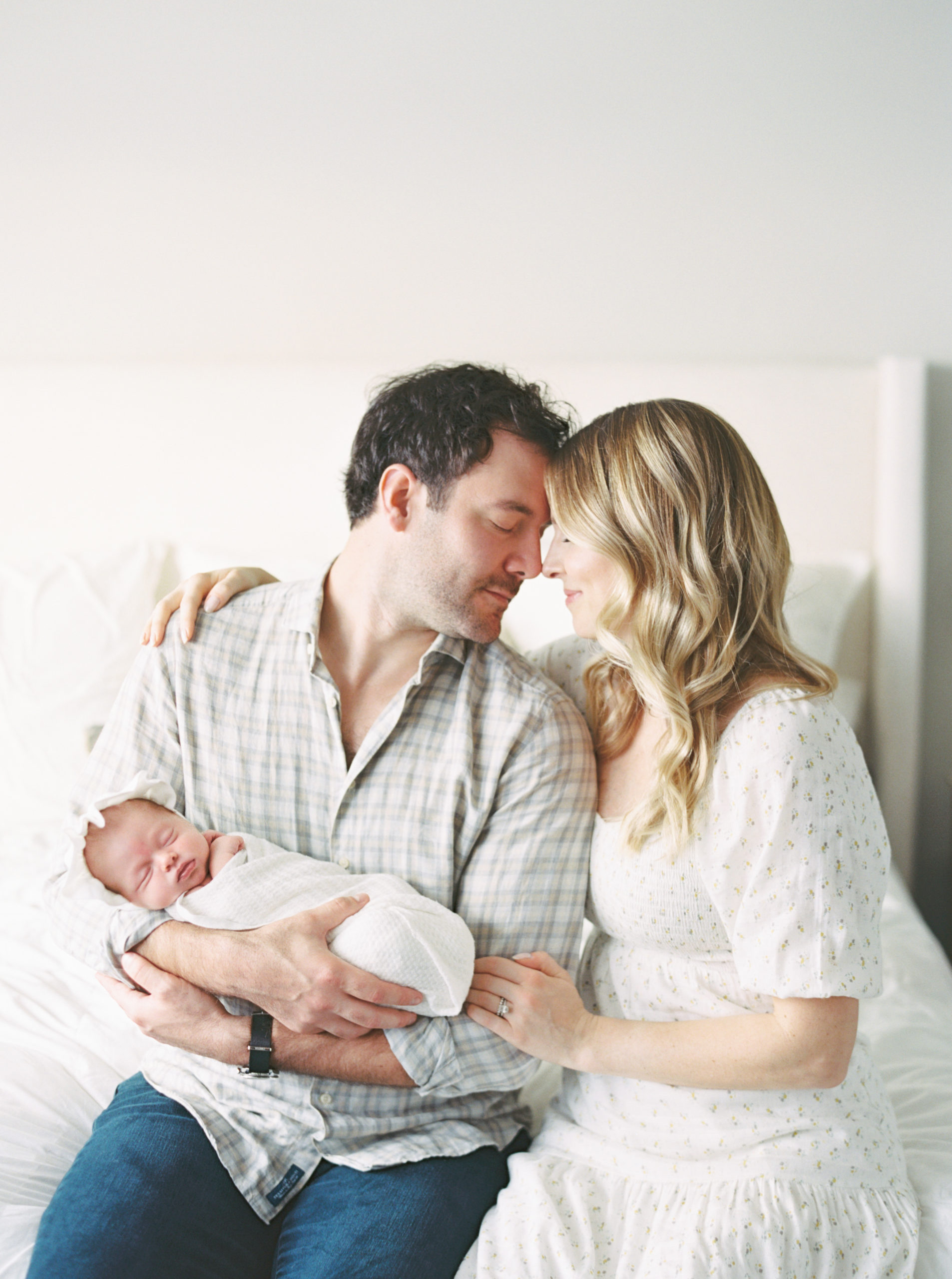 Mother and Father cuddling baby in a beautiful, bright, Milwaukee bedroom