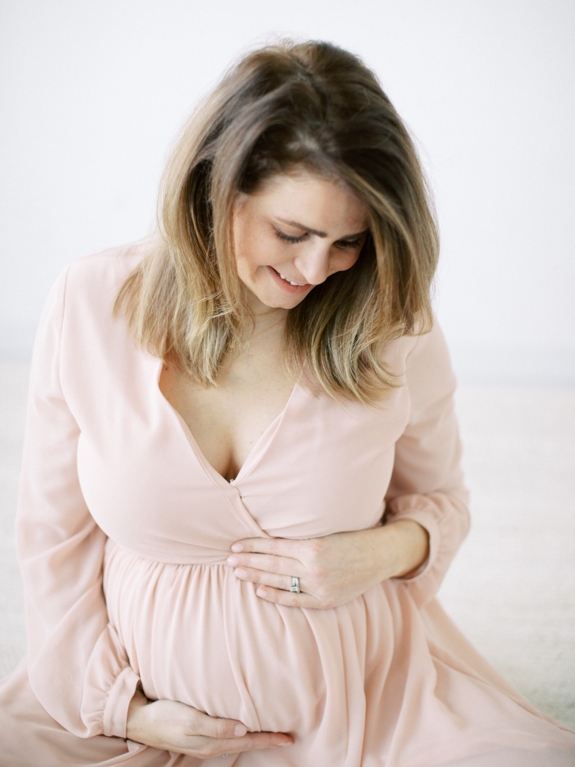 expecting mother's beautiful belly in pink dress in white studio taken by Milwaukee maternity photographer talia laird photography